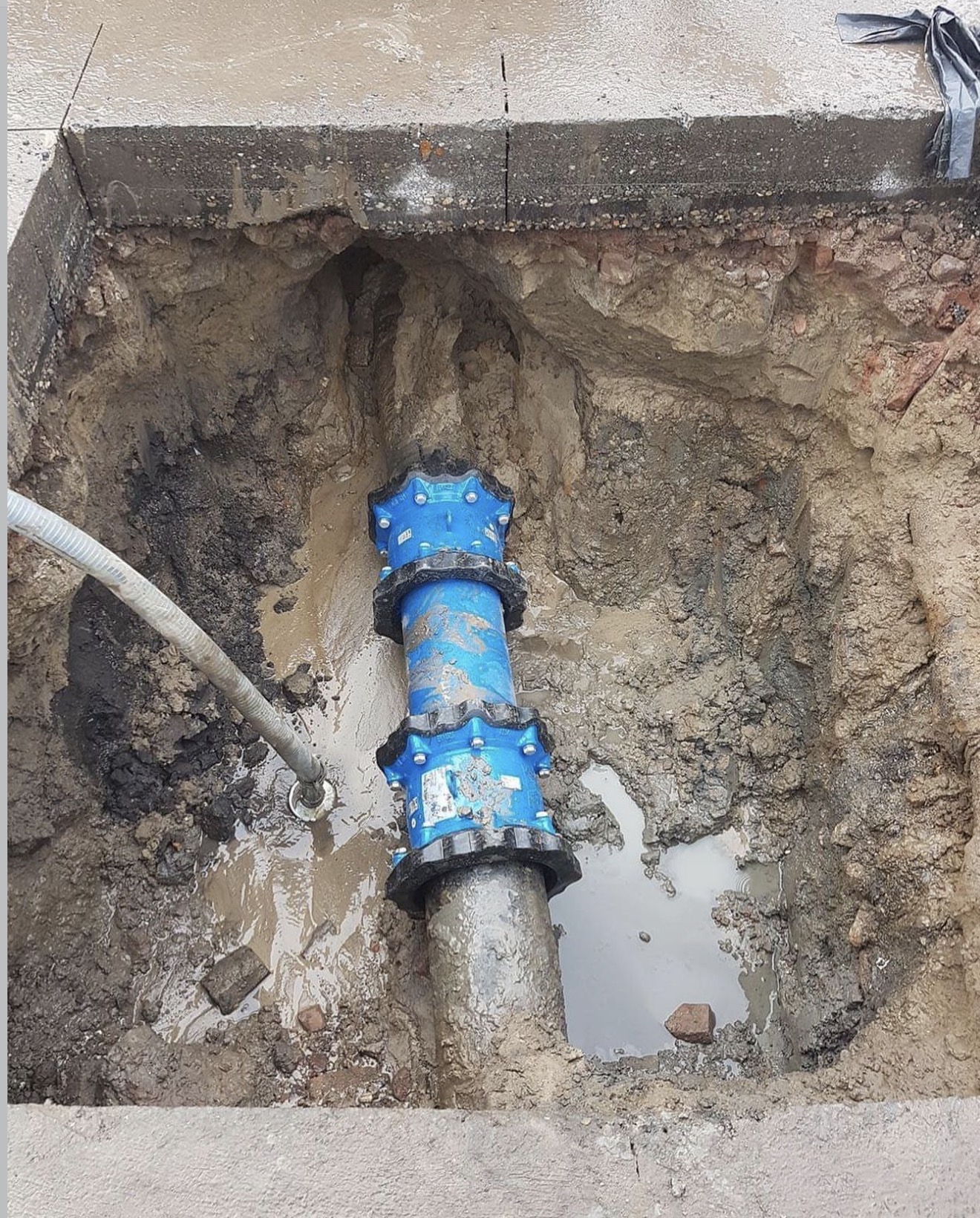 Open sleuf met blauwe leidingkoppeling voor riolering en waterleiding
